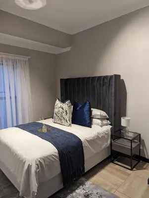 a bedroom with a large bed with blue pillows at Spacious 2 Bedroom Apartment in Midrand, Waterfall City - Business and Family friendly - 1 Elizabeth Place in Midrand