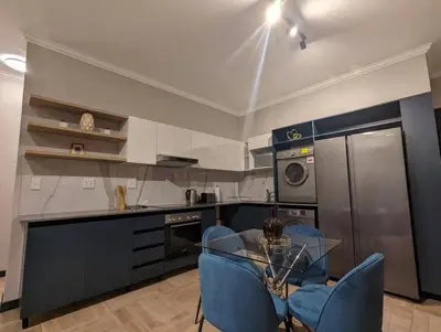 a kitchen with a glass table and blue chairs at Spacious 2 Bedroom Apartment in Midrand, Waterfall City - Business and Family friendly - 1 Elizabeth Place in Midrand