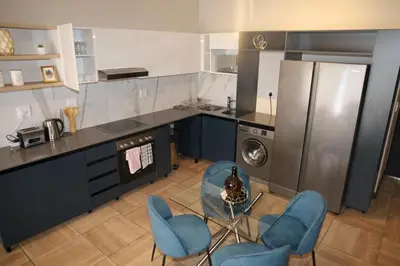 a kitchen with blue chairs and a table and a refrigerator at Spacious 2 Bedroom Apartment in Midrand, Waterfall City - Business and Family friendly - 1 Elizabeth Place in Midrand