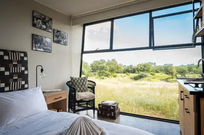 a bedroom with a bed and a chair and a window at Kamoka Camp in Hoedspruit