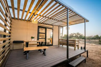 a deck with a pergola and a table and bench at Kamoka Camp in Hoedspruit