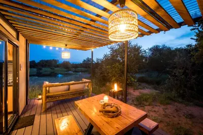 a patio with a table and a bench on a deck at Kamoka Camp in Hoedspruit