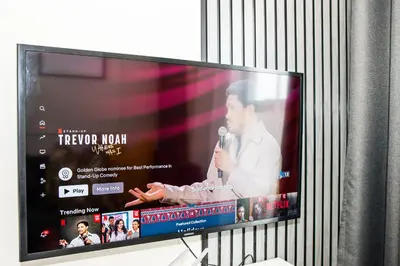 a television screen with a man talking on a microphone at Eirini Elegant - Artemis Apartment Carlswald in Midrand