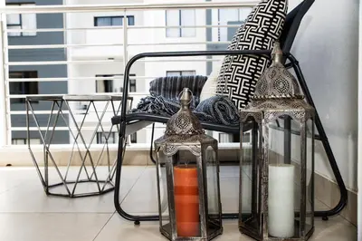two glass lanterns sitting on a chair in a room at Eirini Elegant - Artemis Apartment Carlswald in Midrand