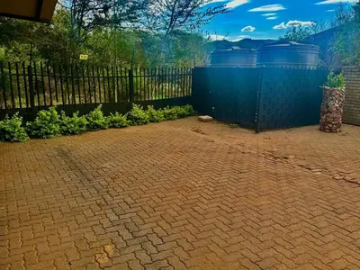 a brick patio with a fence and plants at Valozone70 Guesthouse in Thabazimbi