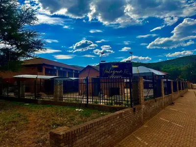 a fence in front of a building with a blue sky at Valozone70 Guesthouse in Thabazimbi