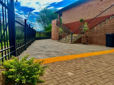 a brick building with a staircase next to a fence at Valozone70 Guesthouse in Thabazimbi