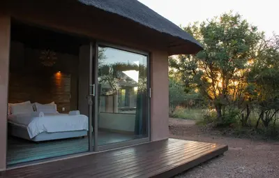 a bedroom with a bed and a sliding glass door at Kudu Lodge in Kromdraai