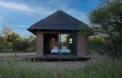 a small tent with a bed in a field at Kudu Lodge in Kromdraai
