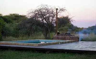 a swimming pool in the middle of a field at Kudu Lodge in Kromdraai
