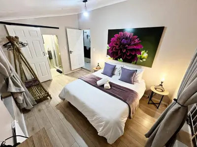 a bedroom with a bed with a flower painting on the wall at Lincoln Moon Guesthouse in Graskop