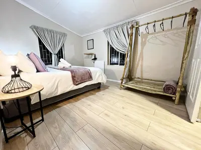 a bedroom with a canopy bed and a wooden floor at Lincoln Moon Guesthouse in Graskop