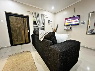 a living room with a couch and a flat screen tv at Lincoln Moon Guesthouse in Graskop