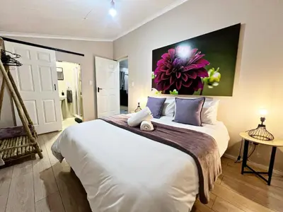 a bedroom with a large bed with a painting on the wall at Lincoln Moon Guesthouse in Graskop