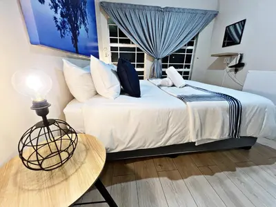 a bedroom with a bed and a table and a window at Lincoln Moon Guesthouse in Graskop