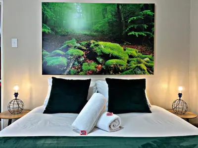 a bedroom with a bed with a painting on the wall at Lincoln Moon Guesthouse in Graskop