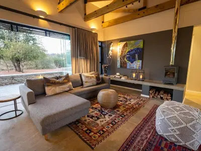 a living room with a couch and a large window at Lavish villa in Hoedspruit with hot tub in Hoedspruit