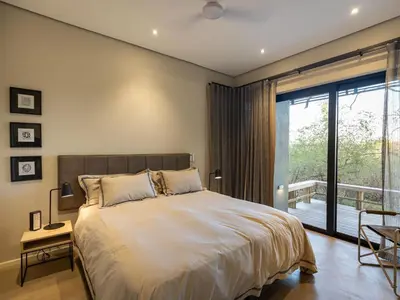 a bedroom with a large bed and a large window at Lavish villa in Hoedspruit with hot tub in Hoedspruit