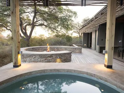 an outdoor patio with a fire pit and a swimming pool at Lavish villa in Hoedspruit with hot tub in Hoedspruit