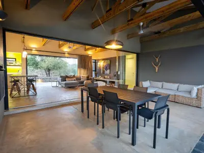 a dining room and living room with a table and chairs at Lavish villa in Hoedspruit with hot tub in Hoedspruit