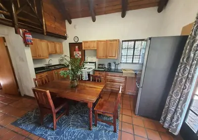 a kitchen with a wooden table and a refrigerator at Luxury Lodge on Sabie River at Kruger Gate! in Huntingdon
