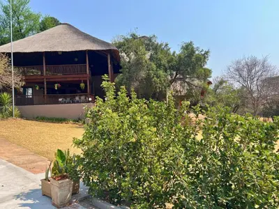a building with a thatched roof and a bush at Motozi Lodge in Pelindaba