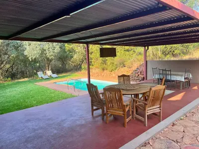 a patio with a table and chairs and a pool at Motozi Lodge in Pelindaba