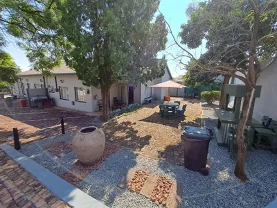 a yard with a trash can and a house at Sleep 'n Go Guesthouse in Mokopane