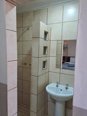 a bathroom with a sink and a shower with a mirror at Sleep 'n Go Guesthouse in Mokopane