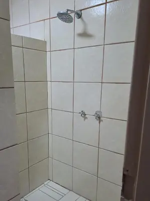 a bathroom with a shower with white tile at Sleep 'n Go Guesthouse in Mokopane