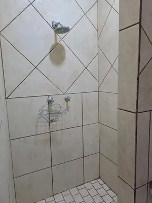 a shower with a glass door in a bathroom at Sleep 'n Go Guesthouse in Mokopane