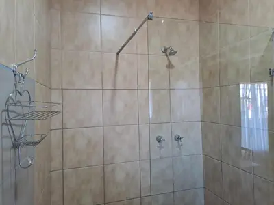 a shower stall with a glass door with a shower at Sleep 'n Go Guesthouse in Mokopane