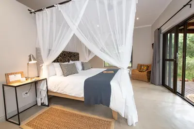 a bedroom with a white bed with a canopy at Nyaleti Lodge in Hoedspruit