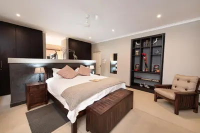 a bedroom with a large bed and a chair at Nyaleti Lodge in Hoedspruit