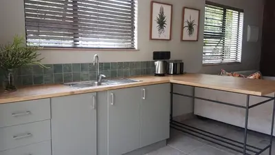 a kitchen with white cabinets and a wooden counter top at Bannockburn Guest Cottage in White River