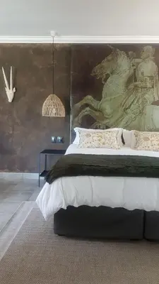 a bedroom with a large bed with a painting on the wall at Bannockburn Guest Cottage in White River