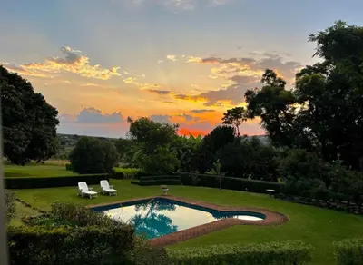 a pool in a yard with a sunset in the background at Bannockburn Guest Cottage in White River