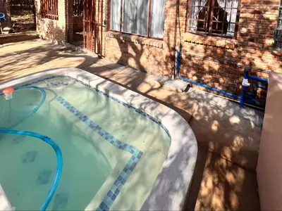 a swimming pool in front of a brick building at Bundu in Marloth Park