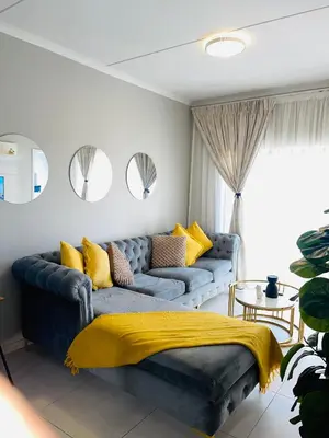 a living room with a blue couch with yellow pillows at Dubai in Midrand