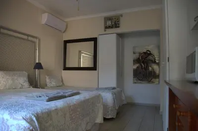 a bedroom with two beds and a tv on the wall at Xaviera Guest House in Pretoria