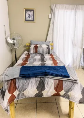 a bed in a bedroom with a fan at Stamvrug 9 B in Nelspruit