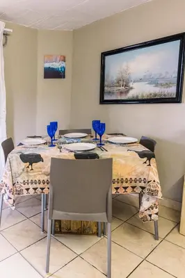 a dining room with a table with blue glasses on it at Stamvrug 9 B in Nelspruit