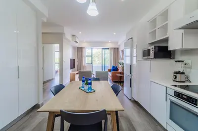 a kitchen and dining room with a wooden table and chairs at STAY Menlyn in Pretoria