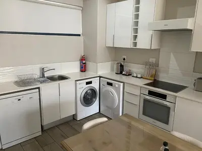 a white kitchen with a washing machine and a sink at STAY Menlyn in Pretoria
