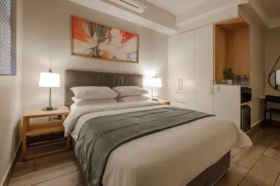 a bedroom with a large white bed with two lamps at STAY Menlyn in Pretoria