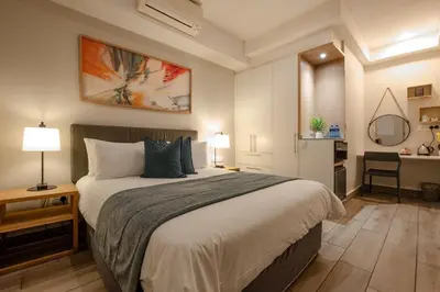 a bedroom with a large bed with a desk and a kitchen at STAY Menlyn in Pretoria