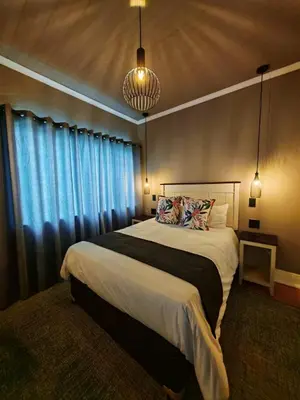 a bedroom with a large bed with blue curtains at Dunkeld East in Dullstroom