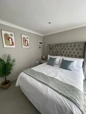 a bedroom with a large white bed with blue pillows at Spacious stay-in bachelor apartment in Kempton Park