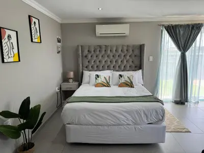 a bedroom with a large bed and a large window at Spacious stay-in bachelor apartment in Kempton Park