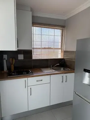 a kitchen with white cabinets and a sink and a window at Spacious stay-in bachelor apartment in Kempton Park